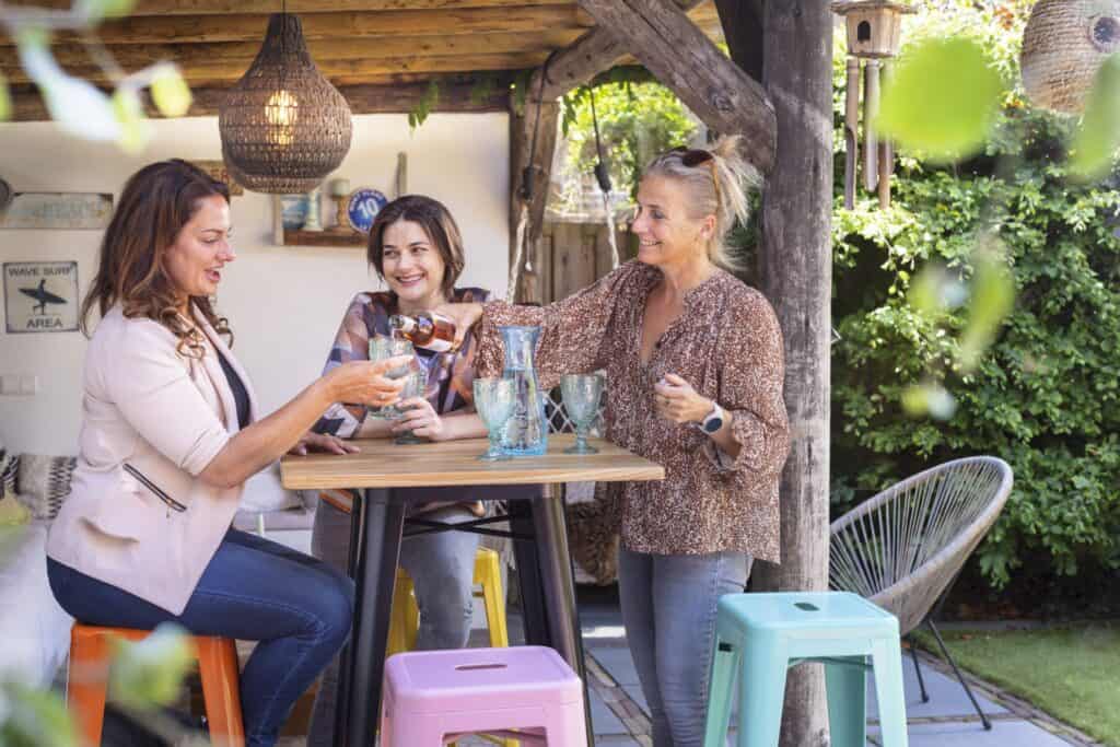 tuinfeestje met mensen die aan een statafel staan met barkrukken